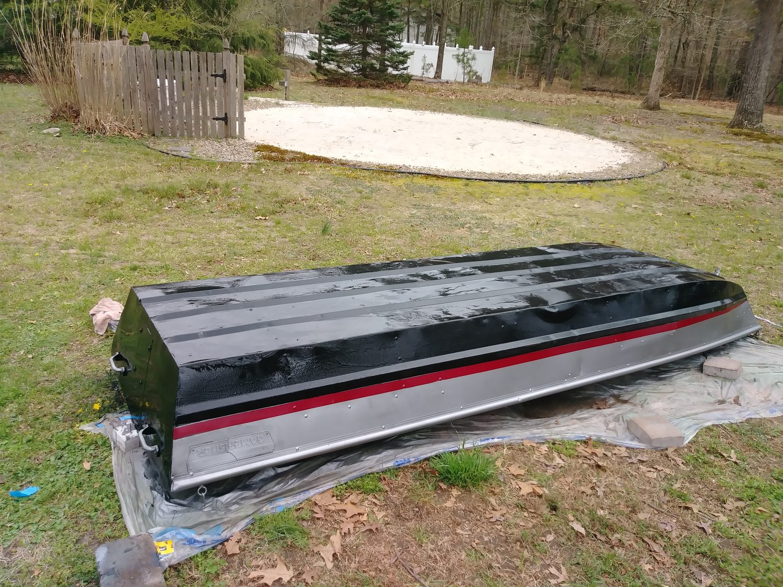 Black-painted hull with red pinstripe, further along in the yard